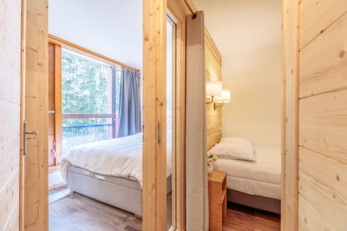Portes de chambres en bois ouvertes sur les chambres de l'appartement Cosyarc à Bourg-Saint-Maurice, avec vue montagne depuis le balcon