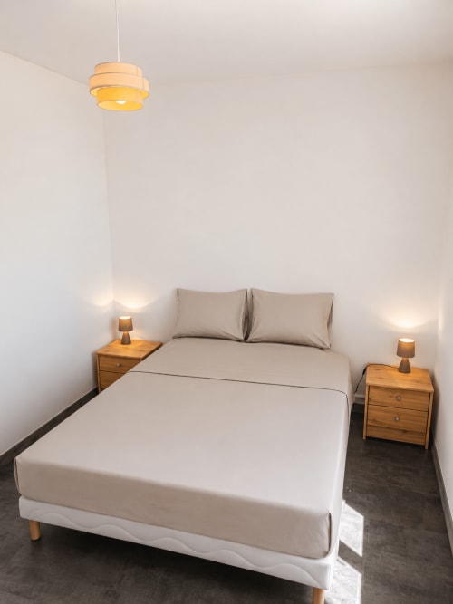 Modern bedroom at Domaine de Beau Site with queen bed, wooden nightstands, pendant light, and minimalist decor in