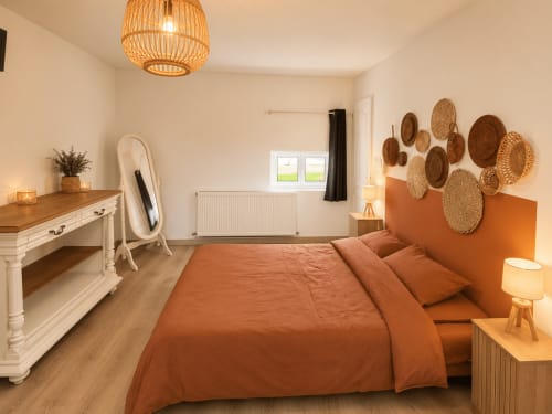 Warm cottage bedroom at Domaine de Beau Site with terracotta bedding, woven basket wall décor, and wooden furnishings
