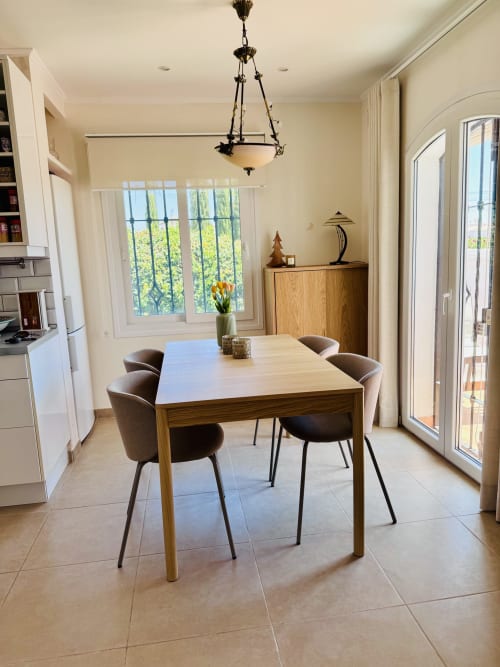 Comedor moderno en villa de Nerja con mesa de madera, sillas marrones, lámpara colgante y vistas al mar a través de amplios ventanales
