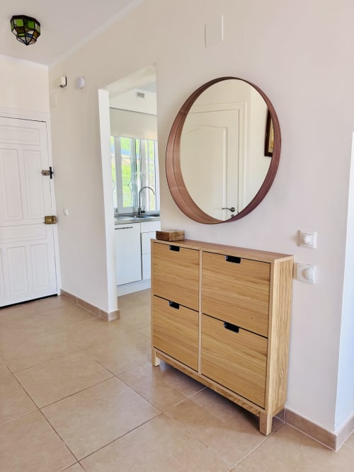 Recibidor moderno con zapatero de madera, espejo redondo y suelos de baldosa en villa de Nerja Holiday Homes
