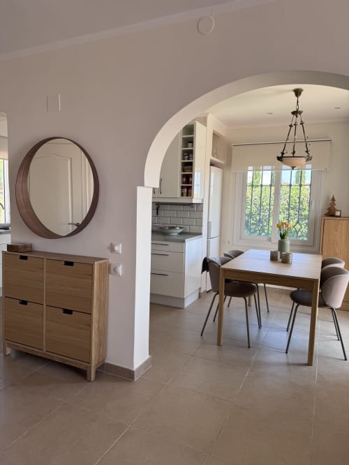 Comedor de villa moderna en Nerja con mesa de madera, sillas contemporáneas, espejo redondo y cocina abierta con vistas al mar