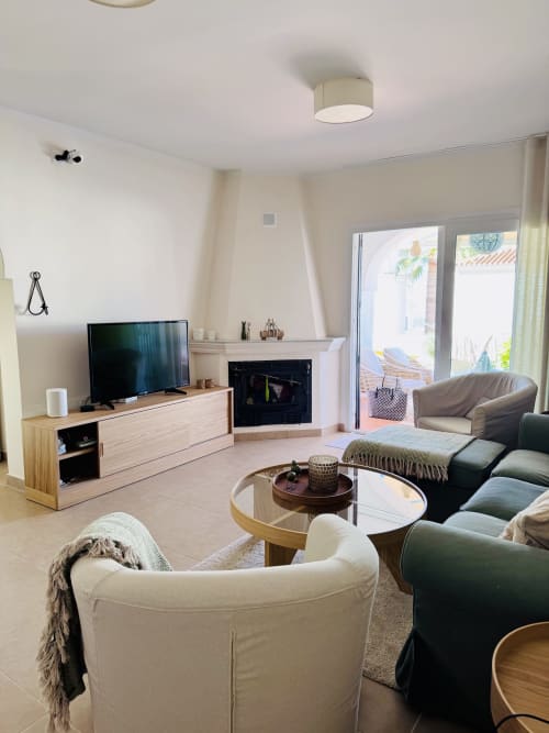 Luminoso salón moderno de villa en Nerja con cómoda sala de estar, chimenea, TV y puertas con vistas al mar hacia la terraza