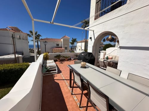 Amplia terraza de villa en Nerja Holiday Homes con vistas al mar, zona de comedor, BBQ y arquitectura mediterránea