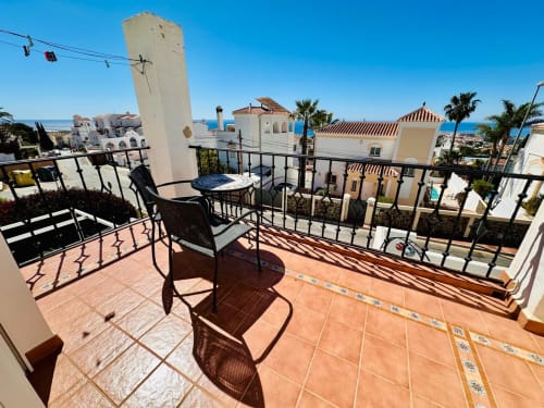 Terraza acogedora de villa en Nerja con vistas al mar, arquitectura mediterránea, palmeras y cielo azul