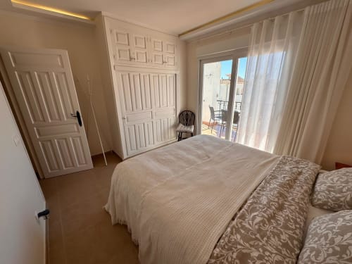 Dormitorio luminoso en villa de Nerja con balcón con vistas al mar, armario blanco y cómoda ropa de cama