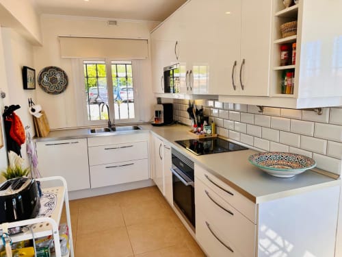 Cocina moderna y completamente equipada en villa de Nerja con gabinetes blancos, electrodomésticos de acero inoxidable y salpicadero de azulejos