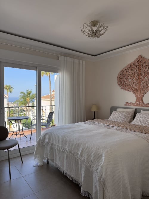 Elegante dormitorio en villa de Nerja con vistas al mar, mobiliario contemporáneo, arte decorativo en pared y paisaje costero visible