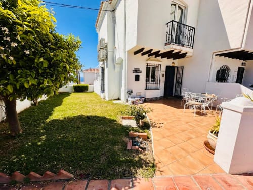 Acogedora villa en Nerja con patio de barro, paredes encaladas, jardín exuberante y vistas al mar