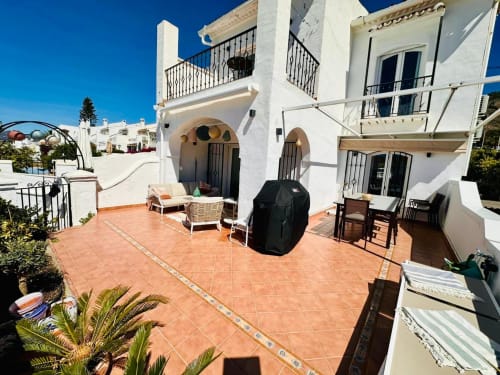 Acogedora terraza de villa en Nerja con baldosas de barro, arquitectura blanca mediterránea, patio amueblado y vistas al mar