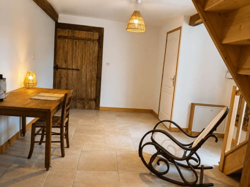 Cozy living room in La Longère cottage at Domaine de Beau Site with wooden dining table, rocking chair, and rustic decor in