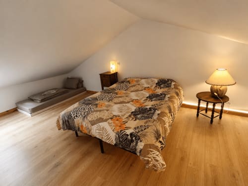 Spacious attic bedroom at Domaine de Beau Site cottage with patterned bedding, wooden floors, and warm lighting in