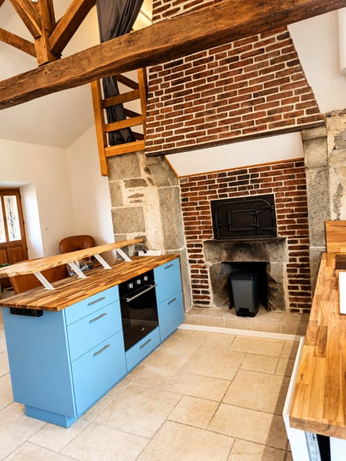 Modern kitchen with blue cabinets and wood beams in La Longère cottage at Domaine de Beau Site, Peyrat-de-Bellac