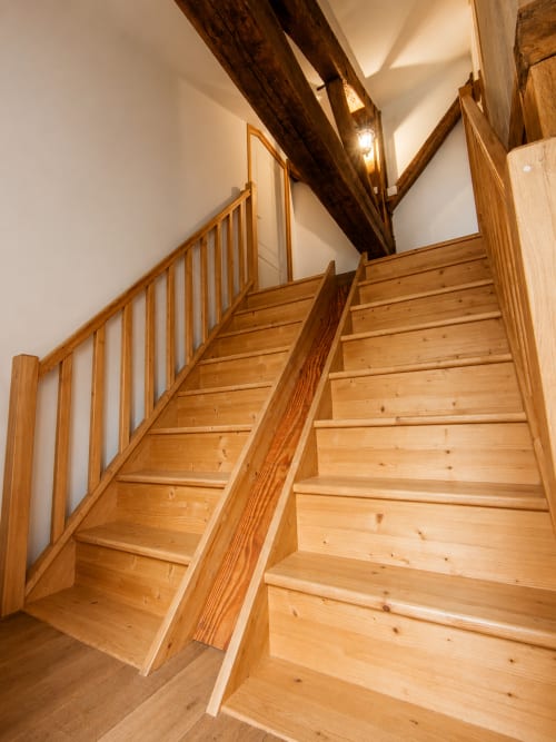 Wooden staircase with rustic beams at Domaine de Beau Site cottage La Longère in Peyrat-de-Bellac
