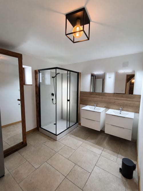 Modern bathroom in La Longère cottage at Domaine de Beau Site with double vanities, black framed shower, and warm lighting