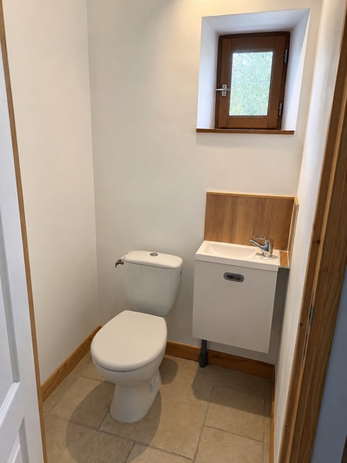 Modern bathroom with white toilet and sink, wooden accents, at Domaine de Beau Site cottage in Peyrat-de-Bellac