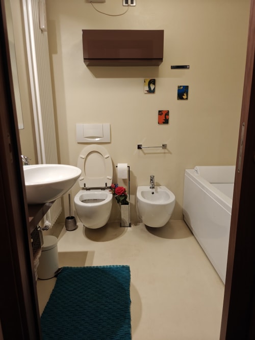 Bagno moderno nell'appartamento LHE Coco's Home di Cesena con wc, bidet, lavabo, vasca e tappetino blu teal