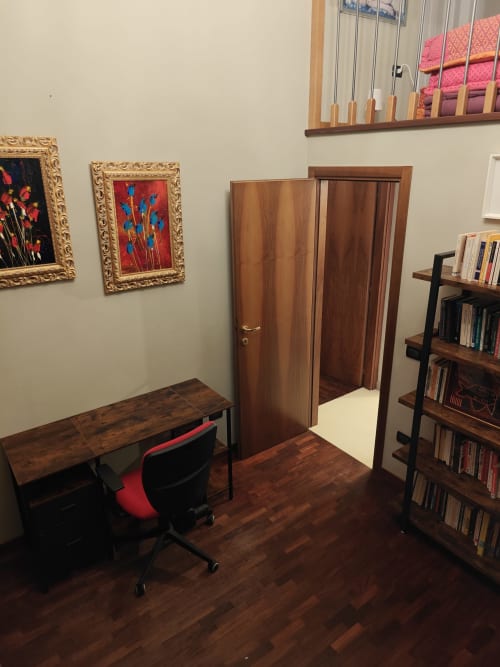 Ufficio in appartamento con scrivania in legno, sedia rossa, librerie e opere d'arte incorniciate presso LHE Coco's Home a Cesena