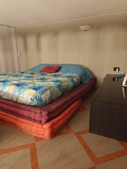 Camera da letto colorata nell'appartamento LHE Coco's Home a Cesena, con biancheria a strati e comò scuro