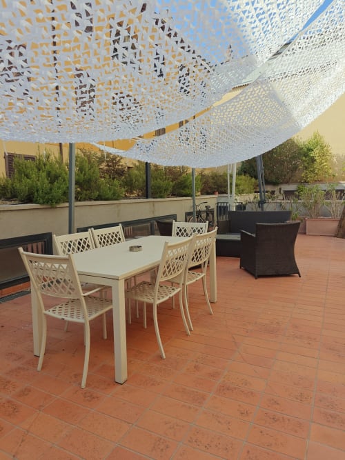 Terrazza panoramica dell'LHE Coco's Home a Cesena con tavolo da pranzo bianco, vela ombreggiante decorativa e vista sulla città