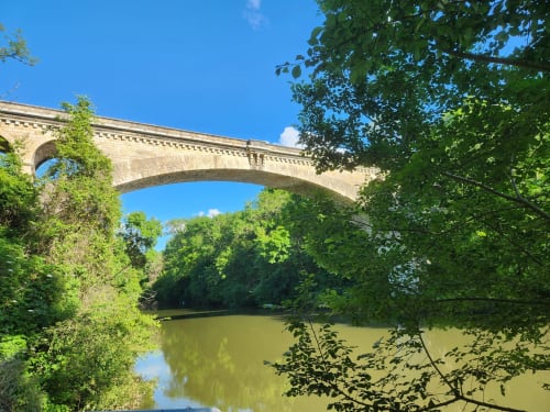 Pont en pierre historique enjambant une rivière bordée de verdure au Domaine Langelet, Saint-Gauzens, France