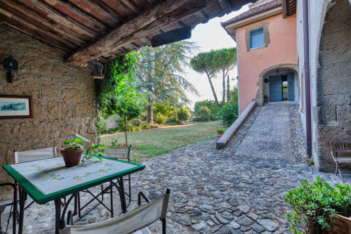 Cortile di Borgo Rinascimento con tavolo da pranzo, edifici in pietra e vista sulla campagna a Farnese, Italia