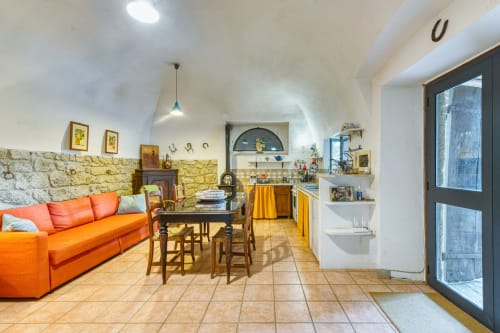 L'appartamento La Scuderia a Borgo Rinascimento a Farnese presenta una zona living open space con divano arancione, tavolo da pranzo e