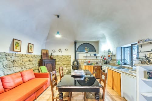 Appartamento La Scuderia a Borgo Rinascimento a Farnese con muri in pietra, divano arancione, tavolo da pranzo e cucina.