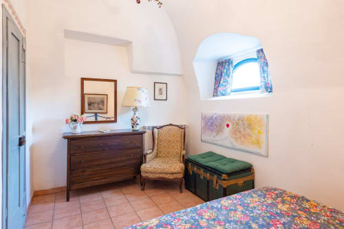 Affascinante camera da letto a Borgo Rinascimento a Farnese con mobili in legno, finestra ad arco e biancheria colorata