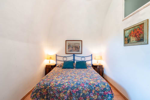 Camera accogliente a Borgo Rinascimento a Farnese con biancheria floreale blu, testata in metallo e illuminazione calda