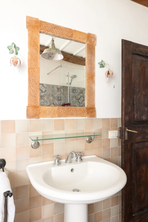 Lavabo del bagno con specchio in cornice di legno ornato presso il Borgo Rinascimento B&B a Farnese, Italia