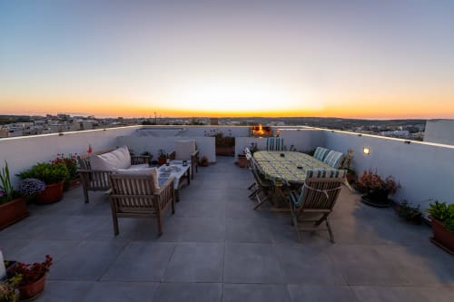 Rooftop terrace at Estrella Lodging in Rabat with sunset city views, wooden furniture, and potted plants