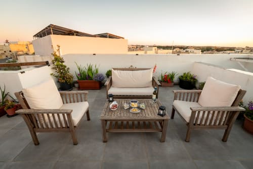 Rooftop terrace at Estrella Lodging in Rabat with wooden seating, potted plants, and city views at sunset