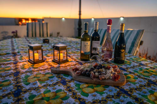 Sunset rooftop terrace at Estrella Lodging in Rabat with wine bottles, charcuterie board, lanterns, and city views