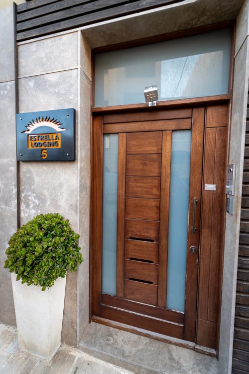 Estrella Lodging hotel entrance in Rabat with wooden door, blue sun logo sign, white planter with green plant