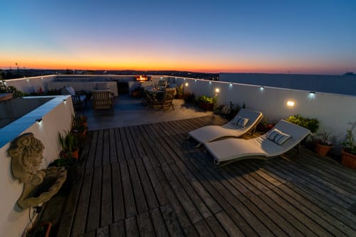 Rooftop terrace at dusk with loungers, white walls, city view, and ambient lighting at Estrella Lodging, Rabat.