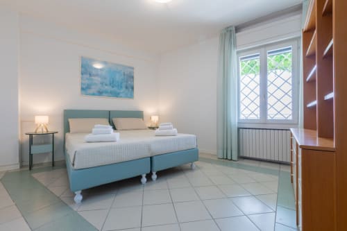Modernes Schlafzimmer in Casa Alba, Hotel Prince Garda in Gardone Riviera mit türkisem Bett, weißer Bettwäsche und Seeblick