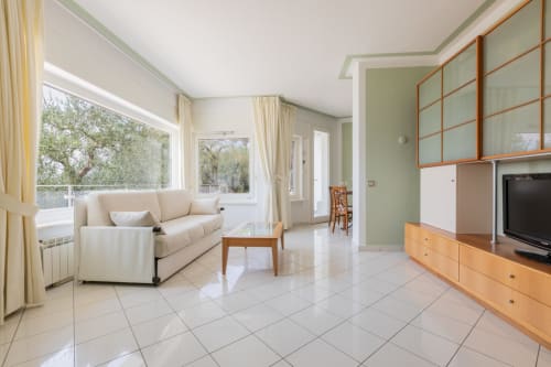 Modernes Wohnzimmer im Casa Alba, Hotel Prince Garda in Gardone Riviera mit cremefarbenem Sofa, Holzmöbeln und Seeblick