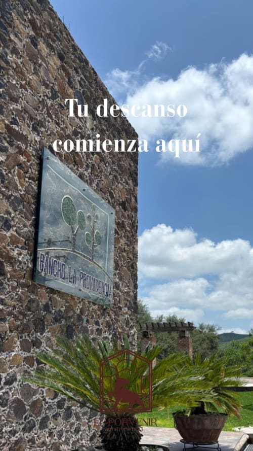 Pared de piedra del Hotel El Porvenir en Querétaro con placa conmemorativa, maceta y cielo azul con nubes