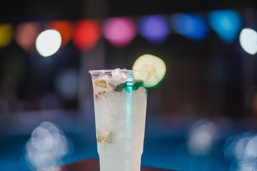 Refrescante cóctel de pepino con hielo en la barra del Hotel El Porvenir, Querétaro, con luces de colores desenfocadas de fondo