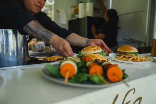 Personal del Hotel El Porvenir preparando hamburguesas y brochetas en el servicio de comedor de Querétaro, México
