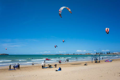 Des cerfs-volants colorés survolent la plage de sable avec des kitesurfeurs et visiteurs sur la côte française près de Villa Triskel