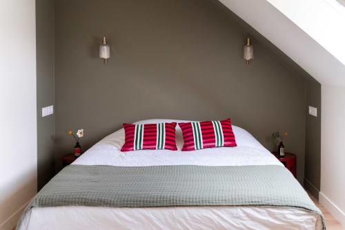 Chambre moderne aux Maisons Noisette avec oreillers rayés rouges, murs neutres et appliques murales à Saint-Pierre-des-Ormes