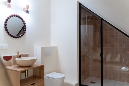 Salle de bain moderne à la Maison Noisette avec meuble-lavabo en bois, miroir à perles et douche en carrelage brun