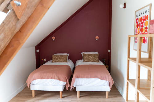 Chambre twin aux Maisons Noisette B&B avec mur d'accent bordeaux, poutres apparentes et mobilier moderne
