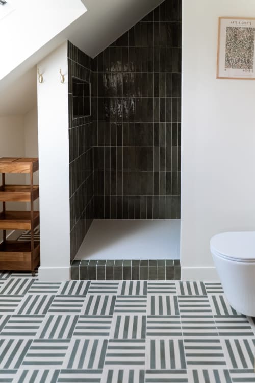 Salle de bain moderne du gîte Maisons Noisette avec douche aux carreaux noirs, carrelage géométrique et plafond mansardé