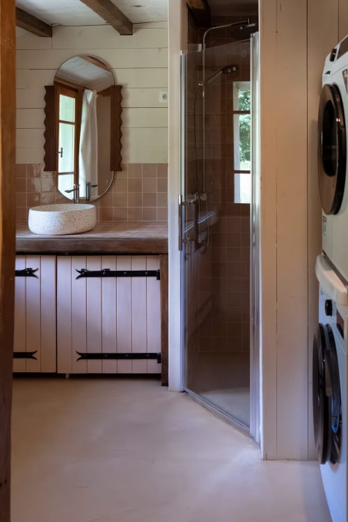 Salle de bain moderne avec vasque ronde, miroir ovale, douche à l'italienne et espace buanderie aux Maisons Noisette B&B,