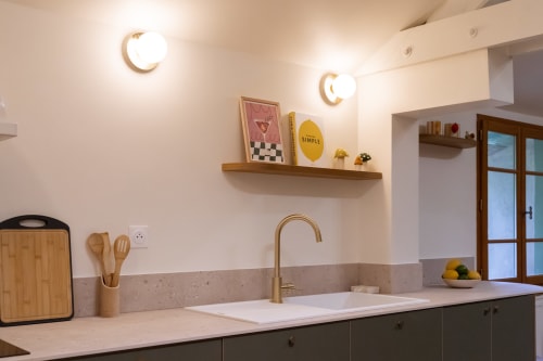 Cuisine moderne avec appliques murales en forme de lune, étagères en bois décorées et robinet en laiton à Maisons Noisette BnB