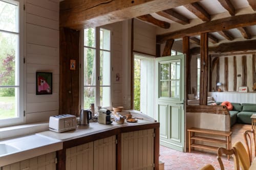 Cuisine rustique aux Maisons Noisette avec poutres apparentes, grandes fenêtres sur les jardins et mobilier d'époque
