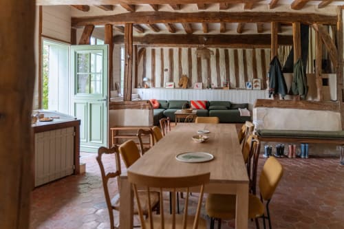 Salle à manger rustique à Maisons Noisette avec poutres en bois, longue table et coin lounge accueillant